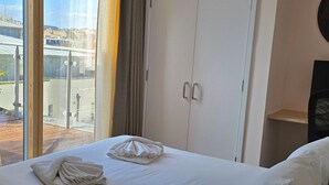 Une chambre d’hôtel avec un grand lit, une armoire et une vue sur la ville grâce à une grande fenêtre.