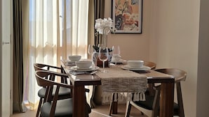 Une salle à manger avec une table mise pour quatre personnes, un vase rempli de fleurs et un tableau accroché au mur.