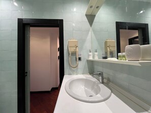 Casa de banho com uma sanita branca, um espelho e um dispensador de toalhas.