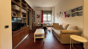 Un salon comprenant un téléviseur, des meubles en bois, un canapé, une table basse et un coin repas avec des chaises et une table.