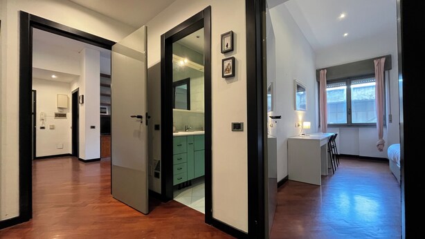 Une pièce spacieuse avec un plancher en bois, une kitchenette, un coin repas et une grande fenêtre avec des rideaux.