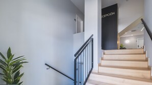 A staircase with a black railing, a reception area with a sign, and a potted plant. - Apartamento Estudio - CORAL ZAHARA Suites by Cadiz4Rentals (Zahara de los Atunes)
