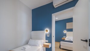 Habitación de hotel moderna con una cama individual, mesitas de noche y aire acondicionado instalado en la pared.