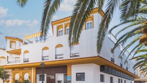 A multi-story building with a yellow and white facade, balconies, and palm trees. - Apartamento Estudio - CORAL ZAHARA Suites by Cadiz4Rentals (Zahara de los Atunes)