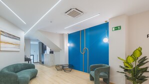 Un espace d’accueil moderne avec un mur d’accent bleu, un comptoir de réception et des coins salon.