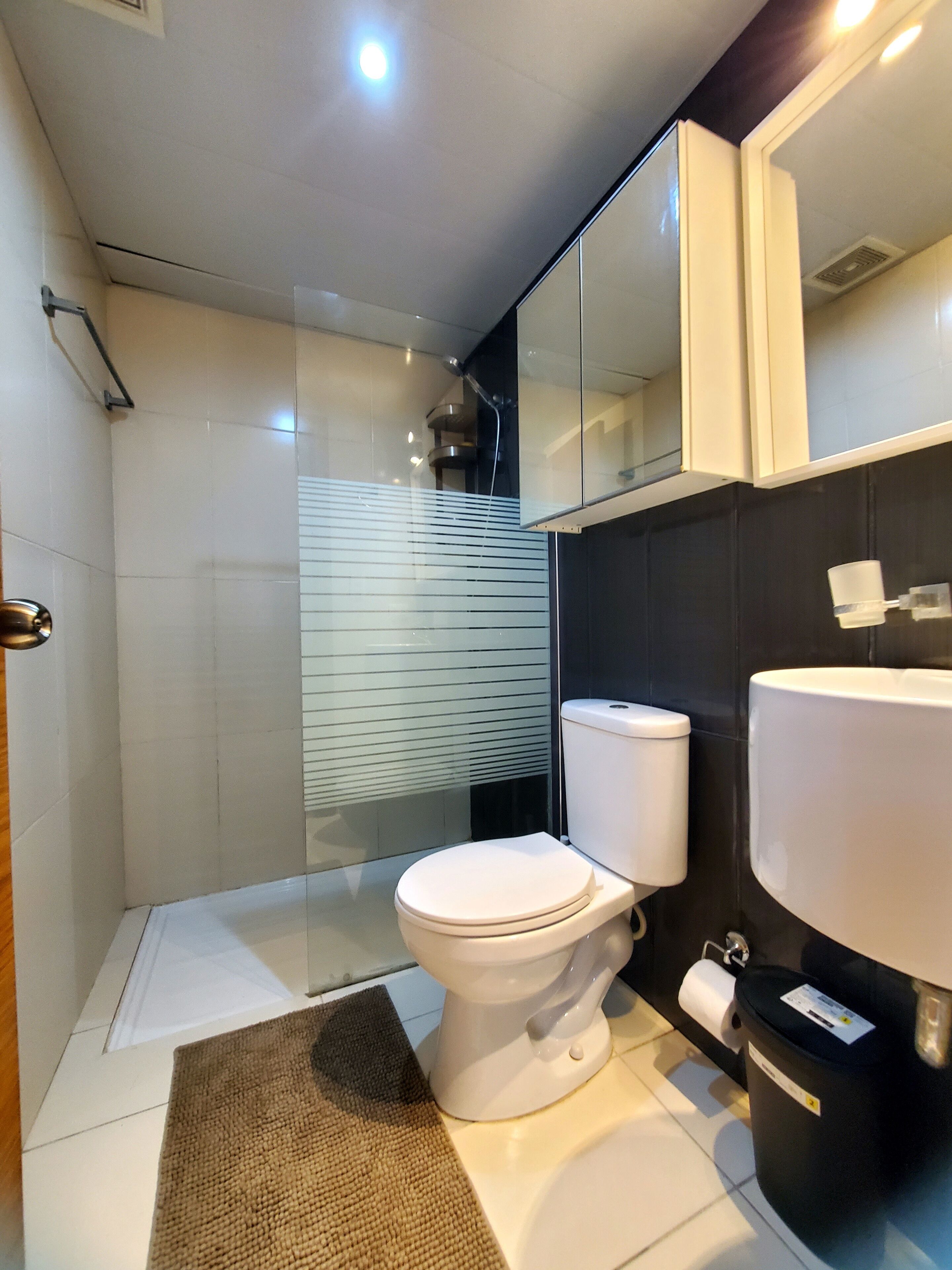 Une salle de bain moderne équipée de toilettes, d’un lavabo et d’une douche à parois en verre.