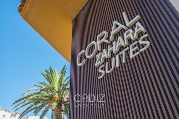 Un edificio con un letrero que dice "CORAL ZAHARA SUITES" y "CADIZ RENTALS".