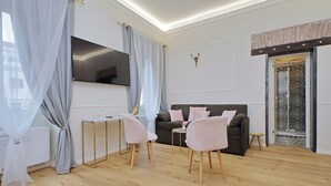 A modern living room with a sofa, two chairs, a TV, and a small table. - Cozy new flat near the Station! (Roma)