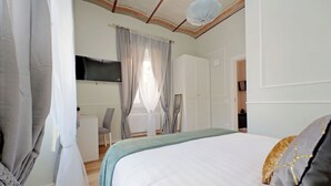 A bedroom with a bed, curtains, a desk, and a television. - Cozy new flat near the Station! (Roma)