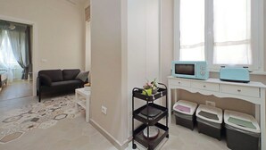 A compact living space with a sofa, a small kitchen area with a microwave and toaster, a trash bin, and a patterned rug. - Cozy new flat near the Station! (Roma)