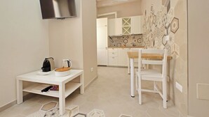 A compact kitchen with white cabinets, a tiled backsplash, and a small dining area with a white table and chair. - Cozy new flat near the Station! (Roma)