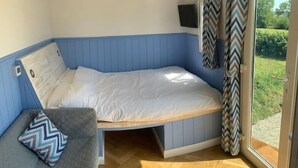 Een slaapkamer met een bed, een kleine zithoek, een televisie en een schuifdeur naar een tuin.