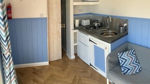 Een kleine keuken met een magnetron, broodrooster, spoelbak en fornuis.