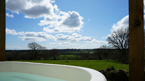 A hot tub with a view of a green field and trees under a partly cloudy sky. - Primrose (With Hot-Tub) (Reynalton)