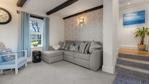 A modern living room with a grey sectional sofa, a white armchair, and a blue patterned rug. - Foxen Holes, Foxenholes cottage, Saundersfoot (Saundersfoot)