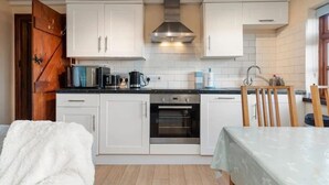 A compact kitchen with white cabinets, a stainless steel range hood, and a built-in oven.