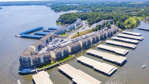 Vue aérienne d’une propriété située au bord de l’eau, comprenant plusieurs bâtiments, des aires de stationnement et des bateaux amarrés.