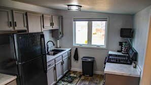 A compact kitchen with a refrigerator, sink, stove, and window.