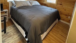 A bedroom with a bed, a nightstand, a window, and a circular light fixture.