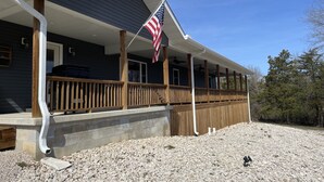 A house with a covered porch, a flag, and a gravel driveway.