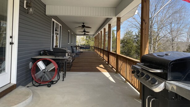 A covered porch with a grill, fan, and ceiling fans.