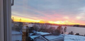 A view of a residential area with houses and a body of water during sunset.