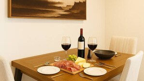 A dining table set with plates, cutlery, a bottle of wine, and a bowl of grapes.