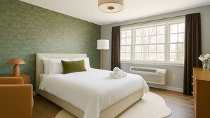 A neatly arranged bedroom with a bed, a bedside lamp, a nightstand, a dresser, and a window with curtains.
