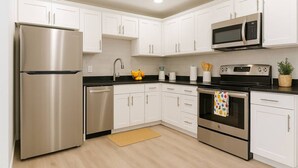 A modern kitchen with white cabinets, stainless steel appliances, and a black countertop.