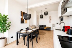 A modern kitchen with a dining area, a sofa, and a potted plant. - DomusNova Finestra Penthouse historic center Turin (Torino)