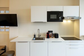 A modern kitchen with white cabinets, a black microwave, a stainless steel sink, a coffee maker, and a toaster. - DomusNova Finestra Penthouse historic center Turin (Torino)