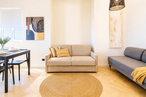 A living room with a sofa, a dining table with chairs, and a round woven rug. - DomusNova Finestra Penthouse historic center Turin (Torino)