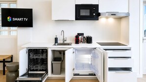 Une cuisine moderne dotée d’appareils électroménagers intégrés, d’un lave-vaisselle et d’un téléviseur affichant la mention « SMART TV ».