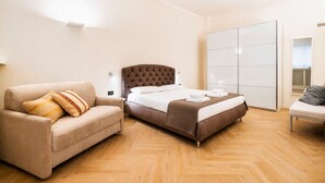 Une chambre d’hôtel comprenant un lit, un canapé, une chaise et une armoire.