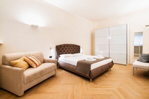 A hotel room with a bed, a sofa, a chair, and a wardrobe. - DomusNova Finestra Penthouse historic center Turin (Torino)