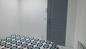 Um quarto com uma cama, uma porta e um claraboia.