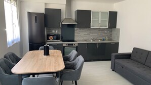 Cozinha moderna com área de refeições, móveis cinza e sofá cinza.