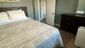 Une chambre à coucher avec un lit, une commode et un tableau accroché au mur.
