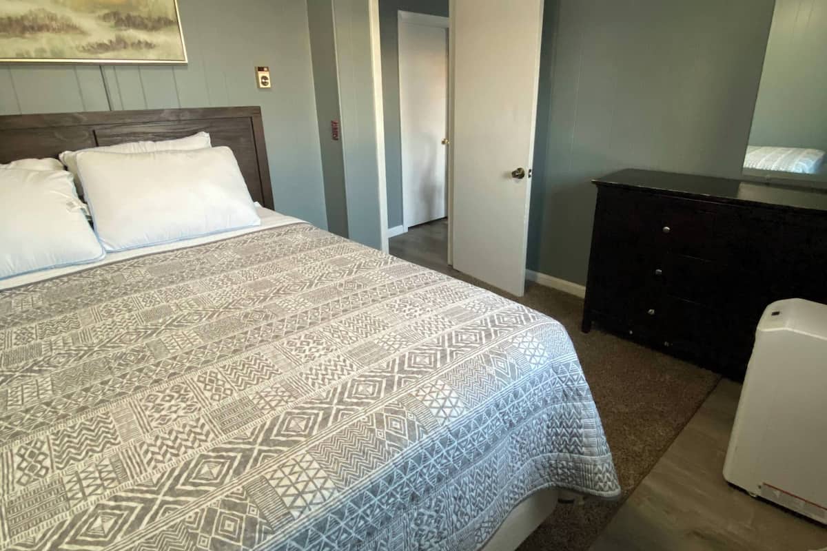 A bedroom with a bed, dresser, and a painting on the wall.