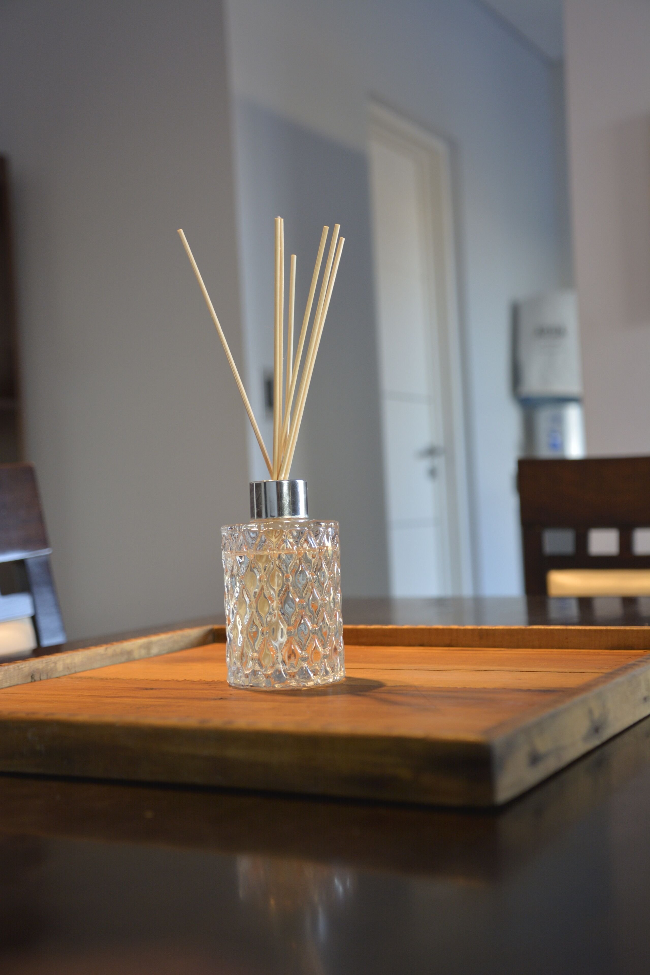Un posavasos de vidrio con palitos de juncos sobre una mesa de madera.