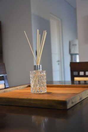 Un posavasos de vidrio con palitos de juncos sobre una mesa de madera.