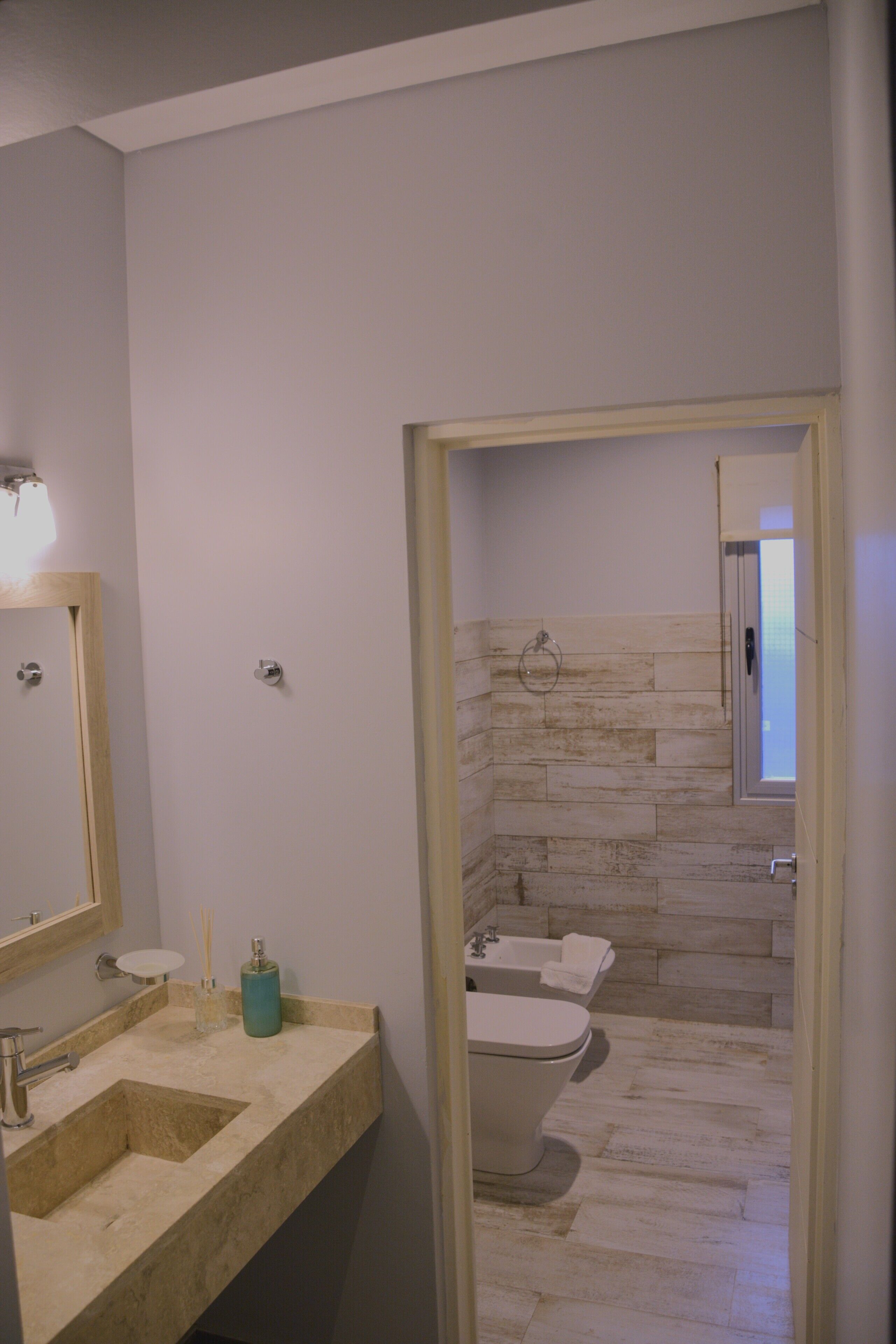 A bathroom with a beige vanity, a mirror, a toilet, and a bathtub.