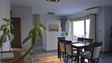 Uma sala de jantar com uma mesa e cadeiras de madeira, um quadro na parede e uma janela com cortinas.