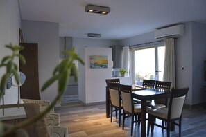 Un comedor con mesa y sillas de madera, un cuadro en la pared y una ventana con cortinas.