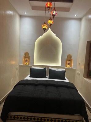 A bedroom with a large bed, a decorative wall, and hanging lamps.