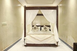 A large bed with a canopy, a wooden headboard, and patterned pillows.