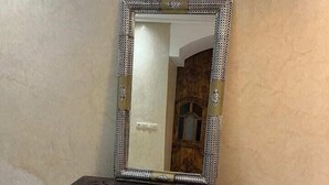 A dark wooden chest with intricate carvings and a large ornate mirror with a patterned frame. - RIAD RKIYA (Tiznit)