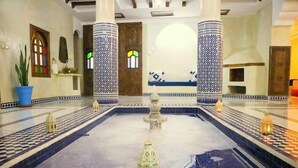 A lobby with a checkered floor, a fountain, and columns with blue and white patterns. - RIAD RKIYA (Tiznit)
