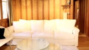 A wooden-paneled room with a white sofa and a round glass coffee table. - Swiss mountain chalet, wooden interior, cosy, with a beautiful view (Evolène)