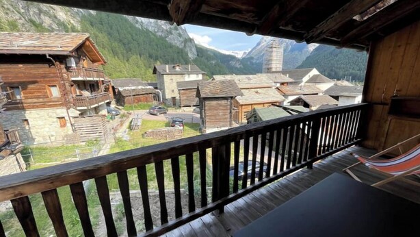 A wooden balcony with a view of a traditional village and mountains. - Swiss mountain chalet, wooden interior, cosy, with a beautiful view (Evolène)